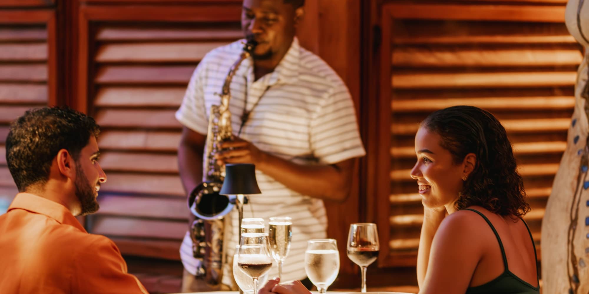 A couple having dinner with a saxophonist playing live music